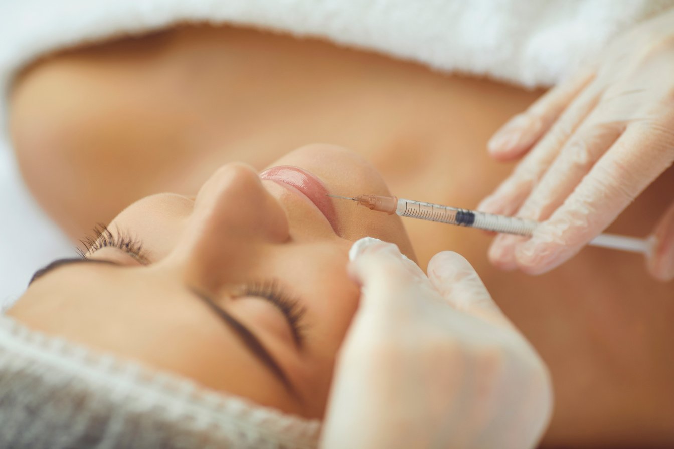 Cosmetologist Making Botox Filler Injection in Female Lips with Syringe in Beauty Salon